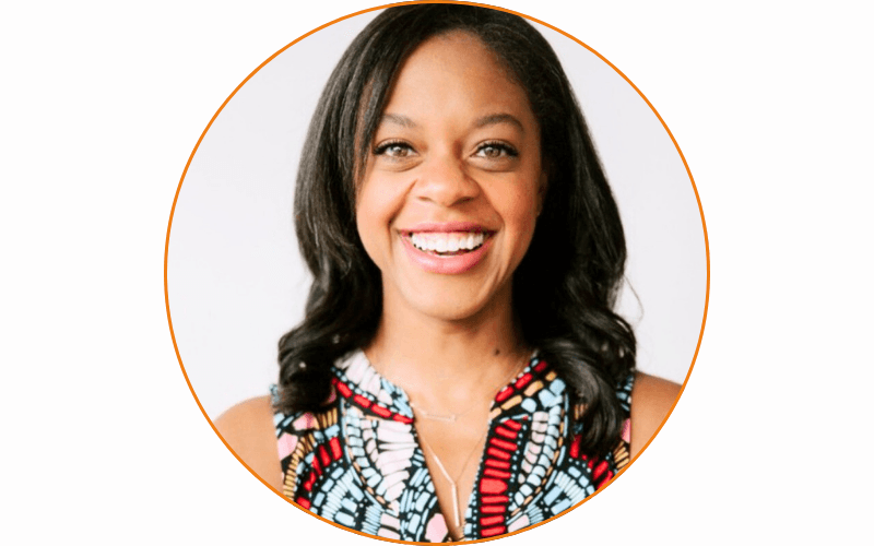 A woman with long, dark hair is smiling directly at the camera. She's wearing a vibrant, multicolored patterned top, ready for her session at the Career Support Career Lab. The background is plain white, and the image is framed within an orange circle.